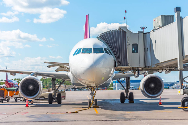 Avión comercial de pasajeros en el estacionamiento en el aeropuerto con una nariz hacia adelante y una pasarela - vista frontal. Servicio y preparación para el vuelo
 - Foto, Imagen