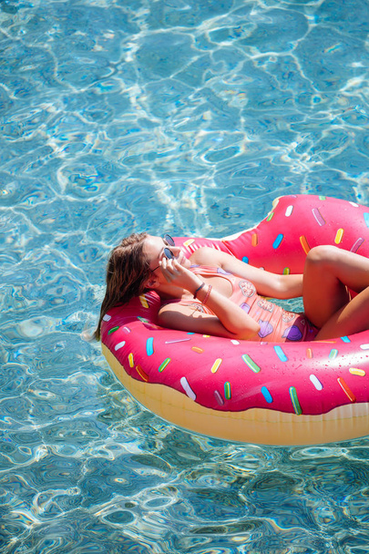 Pretty woman lying on floating ring on Mediterranean sea and enjoying sunbathe. - Foto, afbeelding