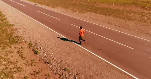 Lage hoogte vlucht voor sportieve man op perfecte asfaltweg - Video