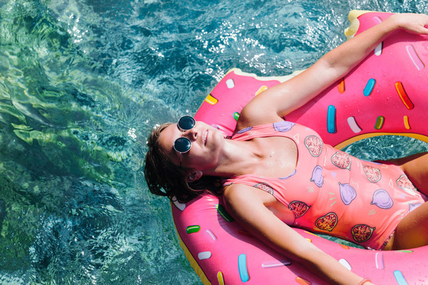 地中海と楽しむフローティング リングに横たわっているきれいな女性の日光浴します。. - 写真・画像