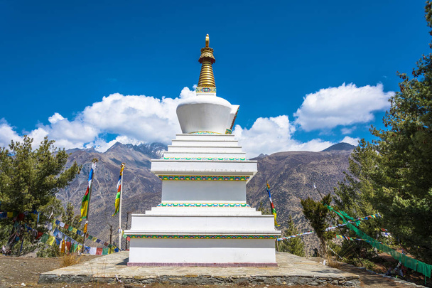 Prachtige witte stenen stoepa tegen de bergen en de blauwe lucht in de Himalaya, Nepal.  - Foto, afbeelding