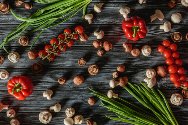 top view of various raw vegetables and mushrooms on wooden tabletop - Foto, Bild