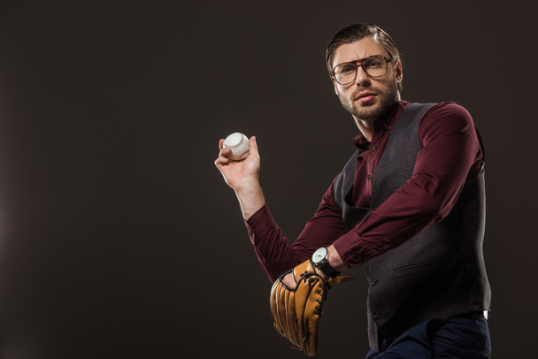 serious businessman in eyeglasses playing baseball isolated on black  - Photo, Image