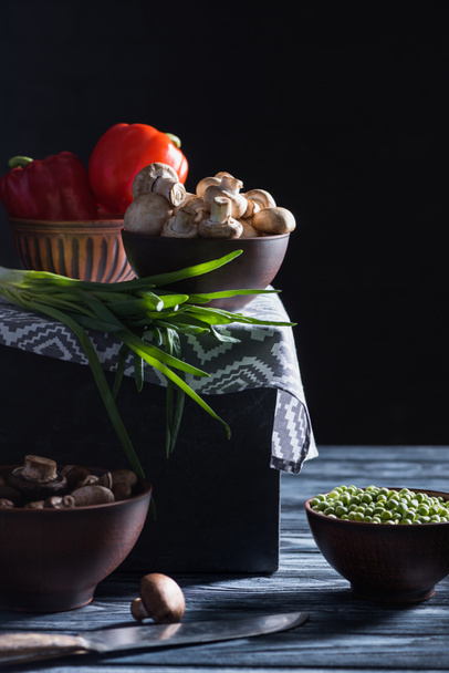 raw champignon mushrooms and different vegetables on table on black - Fotó, kép