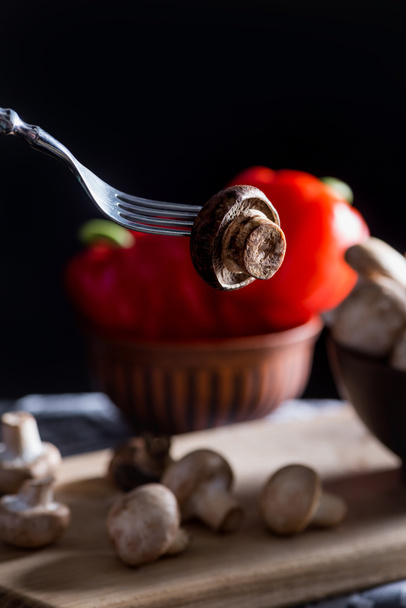 close-up shot of champignon mushroom pierced with fork on dark blurred background - Photo, Image