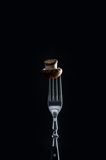 raw champignon mushroom on fork isolated on black - Fotoğraf, Görsel