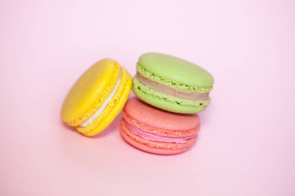 Pink ynd yellow and green french macaroon biscuits on pastel background - Fotoğraf, Görsel