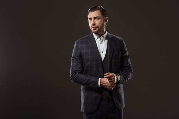 handsome stylish young businessman looking away isolated on black - Zdjęcie, obraz