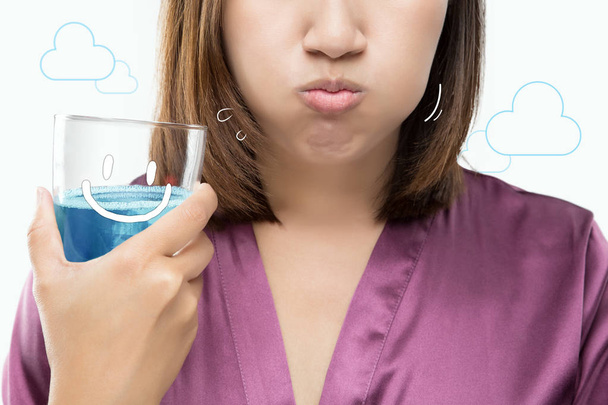 Mujer asiática enjuagando y haciendo gárgaras mientras usa enjuague bucal
. - Foto, Imagen