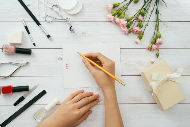 Female hands writing Valentine's day love letter on wooden background - Foto, imagen