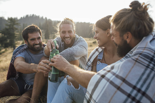 Group of young people drinking beer in nature and looking happy. - Photo, Image