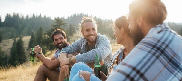 Group of young people drinking beer in nature and looking happy. - 写真・画像