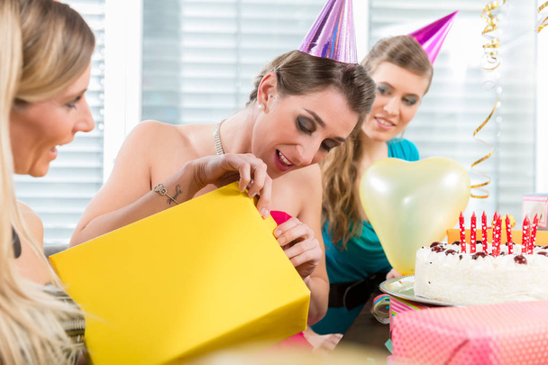 schöne Frau öffnet eine Geschenkschachtel, während sie ihren Geburtstag feiert - Foto, Bild