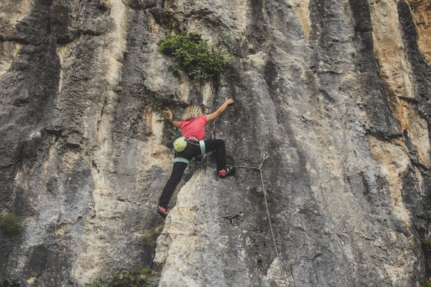 Female rock climber climbing outoors. - Фото, изображение
