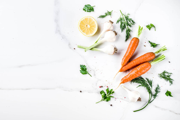 Fondo de cocina con verduras frescas para una cena saludable; zanahorias, hierbas, aceite de oliva, ajo; fondo de mármol blanco tendido plano
 - Foto, imagen