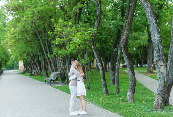 Gentle embraces of young couple in the city park. Beautiful couple perfectly spends time in the city park. - Foto, Imagen
