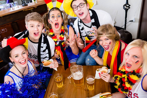 Fotbaloví fanoušci ve sportovní bar sledovat hru s vzrušení - Fotografie, Obrázek