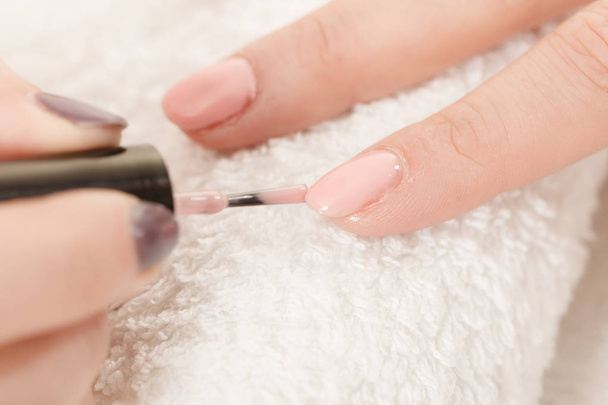 Closeup of beautician painting nails of female client. Woman in beauty spa salon doing manicure - Valokuva, kuva