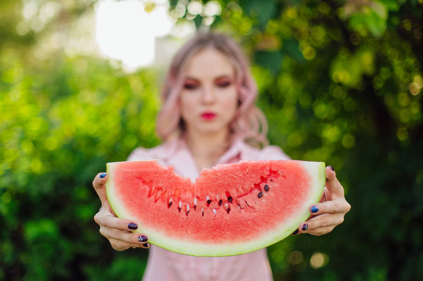 Beautiful smiling young woman with pink hair holding sweet juicy watermelon in hands - Photo, Image