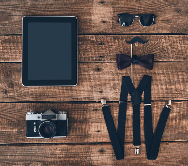 plano plano plano de la tableta digital, cámara fotográfica, tirantes, utilería, pajarita y gafas acostado en escritorio de madera
 - Foto, Imagen