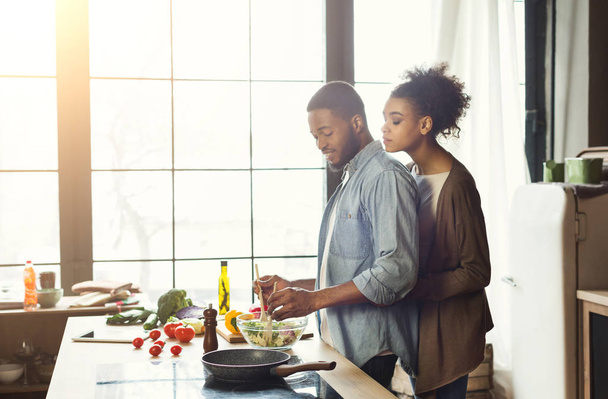 ロフトの台所で調理するアフリカ系アメリカ人カップルを愛する - 写真・画像