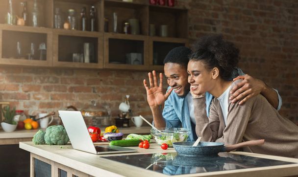 Black couple using laptop and greeting in kitchen - Photo, Image