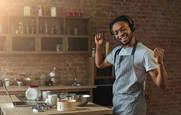Homem negro feliz ouvindo música e dançando na cozinha
 - Foto, Imagem