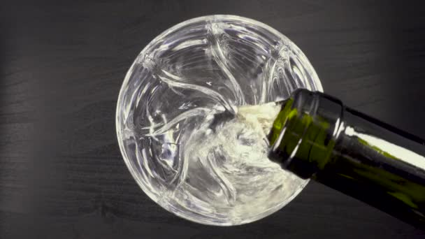 In a glass on a black background pouring wine from a bottle - Video