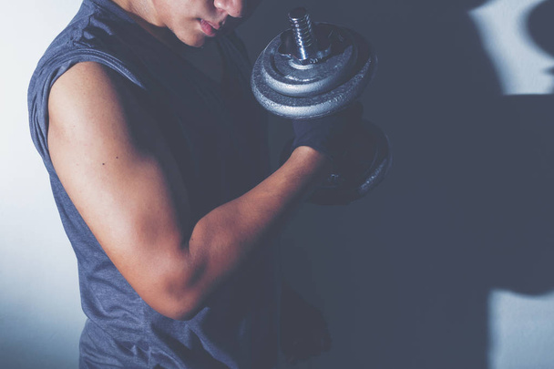 A man Lifting dumbbell for weight training for arm muscle with dark style photo. - Photo, Image