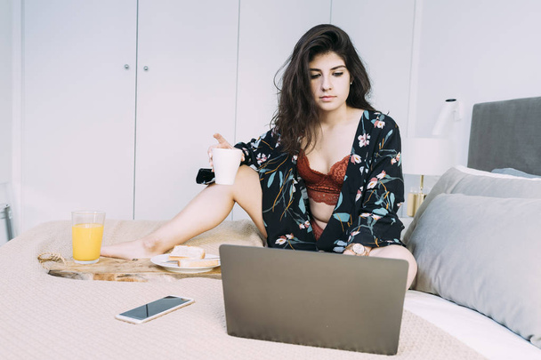 Girl in underwear having breakfast and using laptop in bed - Zdjęcie, obraz