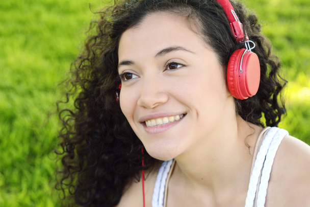 Portrait of young latin woman with headphones listening to music at the park in summer. Enjoying Music. - Foto, afbeelding