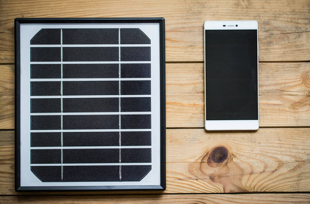 solar panel and smartphone on the wooden table - Foto, imagen