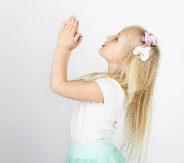 little blond girl folded her hands in prayer to God. A little angel. Side view - Fotó, kép