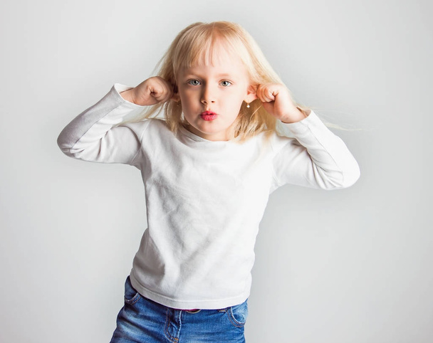 little girl teasing, showing tongue and doing face, on white background, soft focus - Photo, Image