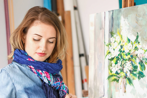 portrait of a girl painter with a palette of colorful paintings in an art studio. Thoughtful artist, creative mood - Foto, immagini