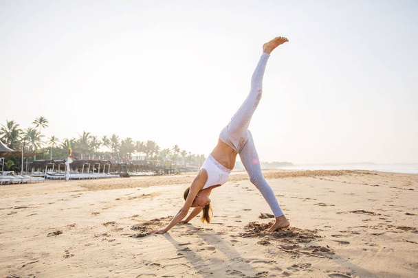 Caucasian woman practicing yoga at seashore of tropic ocean - Foto, Imagen