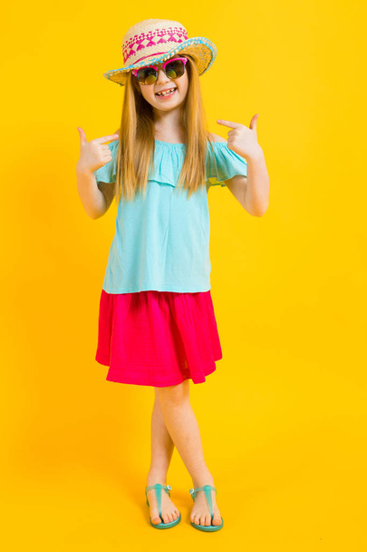 Fille aux cheveux roux sur fond jaune. Charmante fille en vêtements d'été lumineux montre les doigts sur elle-même
. - Photo, image