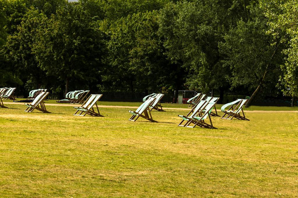 Lege groen en wit gestreepte ligstoelen onder de lente of zomer zon in een park van Londen. Verenigd Koninkrijk - Foto, afbeelding