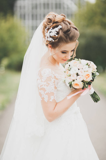 Beautiful bride posing in wedding dress outdoors - Fotografie, Obrázek