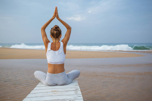 Femme blanche pratiquant le yoga au bord de la mer de l'océan tropique
 - Photo, image