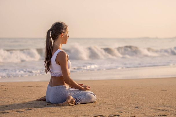Caucasian woman practicing yoga at seashore of tropic ocean - Foto, Bild