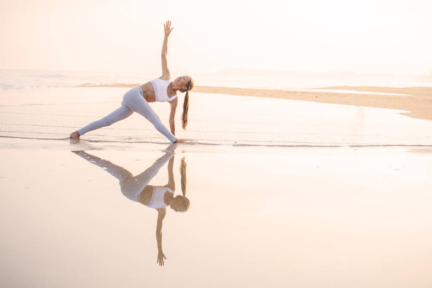 Mujer caucásica practicando yoga en la orilla del mar del océano tropical
 - Foto, Imagen