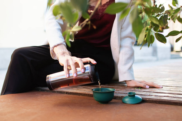 Traveler girl pouring tea in thermos cup, outdoors. Young woman drinking tea at cup. Theme travel. Woman pouring a hot drink in mug. gaiwan - Foto, Imagem