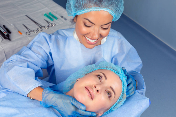 cirurgião plástico verificando rosto de mulher de meia-idade antes da cirurgia estética
 - Foto, Imagem