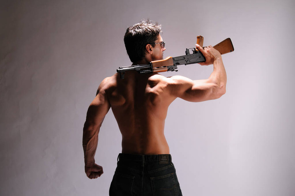 L'uomo sexy tiene stretto un fucile
 - Foto, immagini
