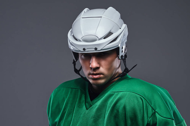 Close-up portrait of a professional hockey player in a protective sportswear and helmet. Isolated on a gray background. - Photo, Image
