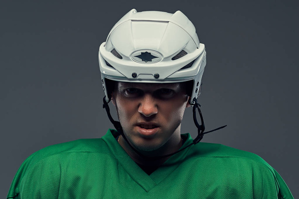 Közelkép portré egy dühös profi jégkorong játékos egy védő sportruházat, és a sisak. Elszigetelt egy szürke háttér. - Fotó, kép