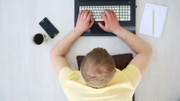 ein freier Mann, der zu Hause auf dem Boden hinter einem Laptop arbeitet - Filmmaterial, Video