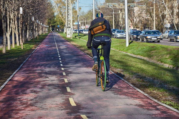 Un ciclista in città si sta muovendo lungo una pista ciclabile. Modalità di trasporto ecocompatibile. Vista dal retro. Bicicletta a velocità fissa
 - Foto, immagini
