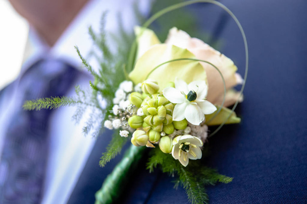 Cheerfully made up corsage with bright flowers. Groom with floral ornament for a wedding. Traditional wedding details for bride, brides sum and guests - Photo, Image